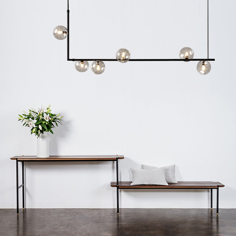Luminaire suspendu linéaire noir minimaliste moderne à 6 lumières avec abat-jour en verre sphérique pour le salon.